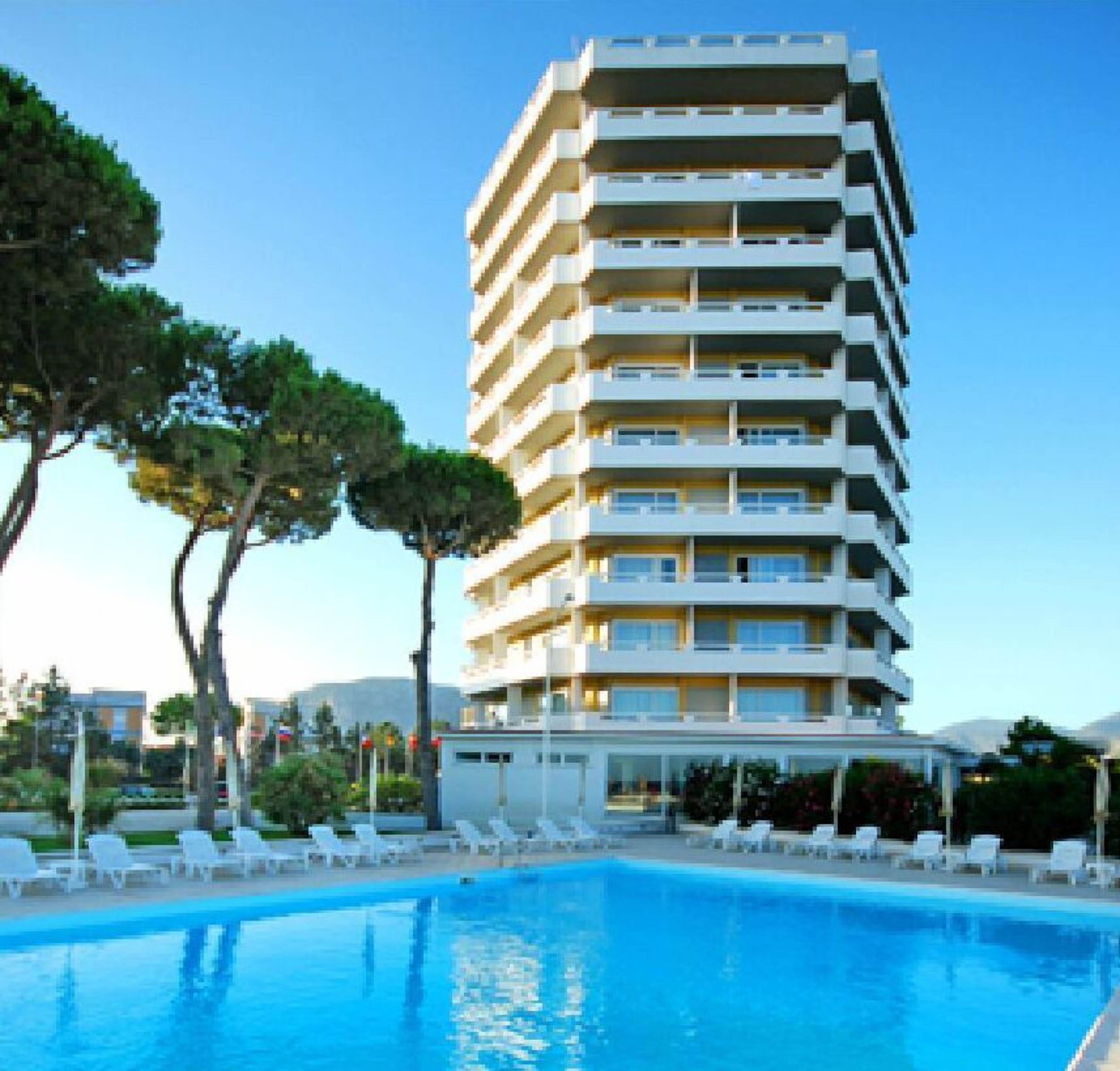 Un hôtel à plusieurs étages doté d’une piscine, entouré d’arbres et d’autres bâtiments.