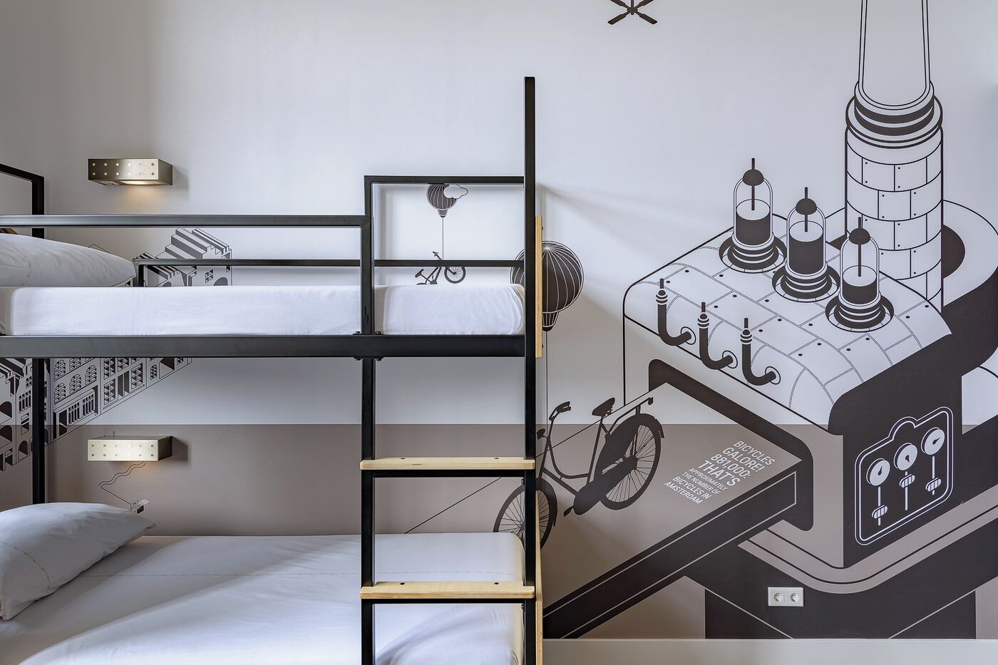 Una cama litera con escalera, una lámpara fijada a la pared, y un mural que muestra una bicicleta y un edificio.