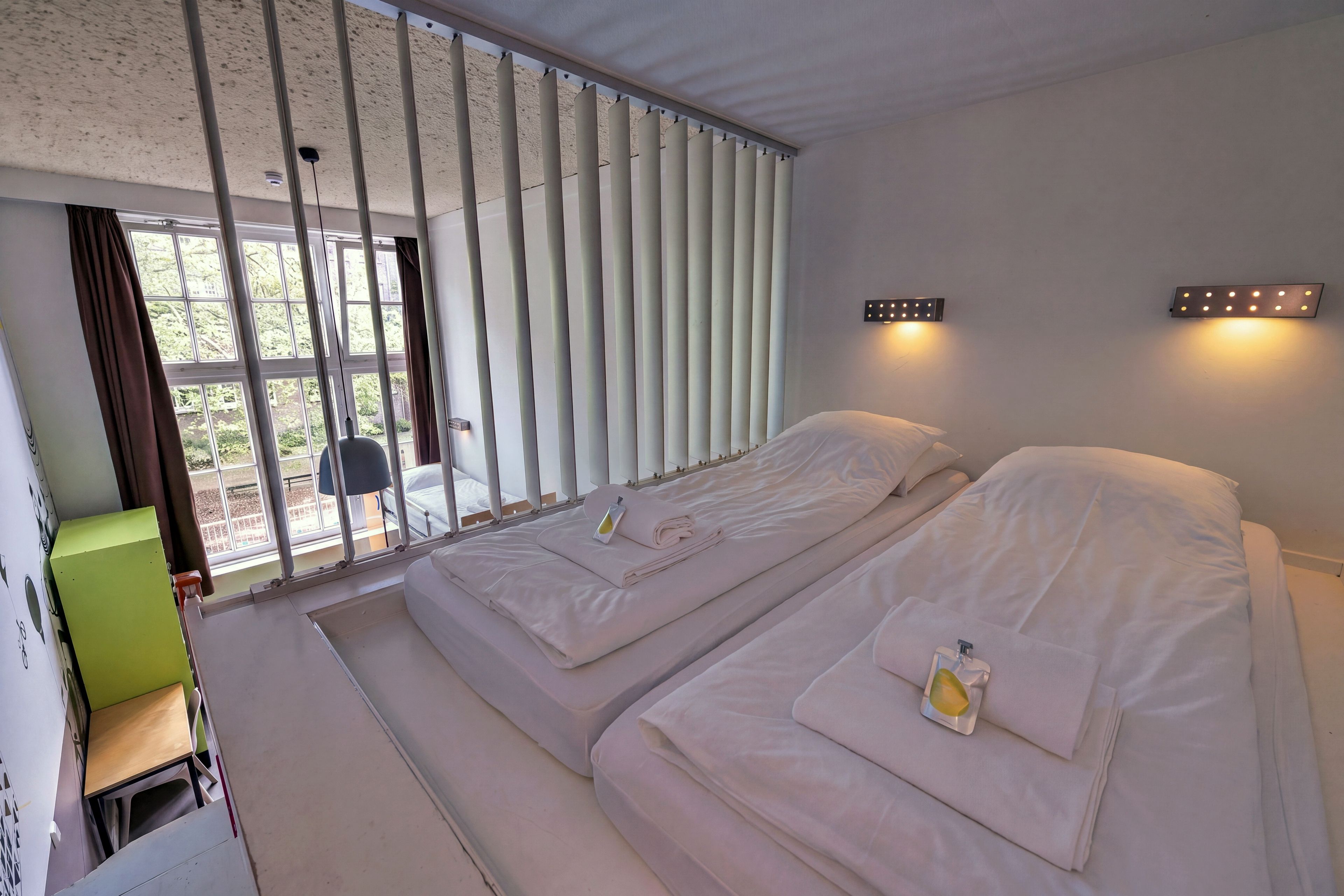 Quarto de hotel com uma cama, uma mesa e vista para o exterior.