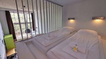 Quarto de hotel com uma cama, uma mesa e vista para o exterior.