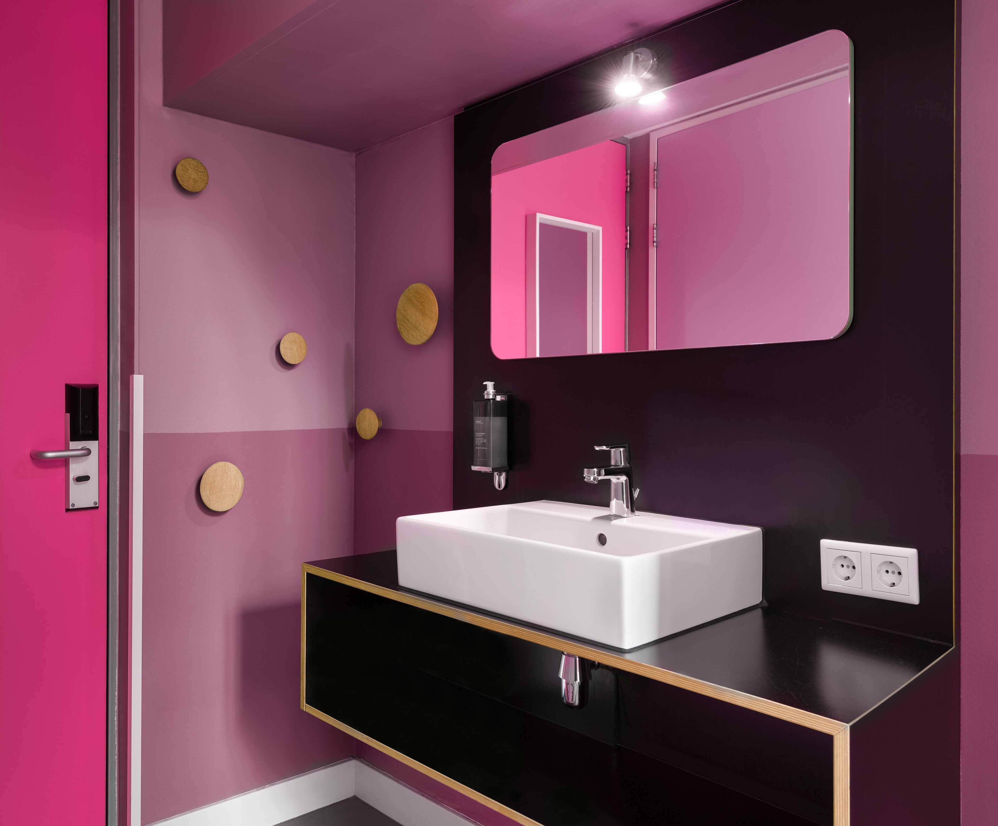 A modern bathroom with a white sink, black countertop, and a mirror above it.