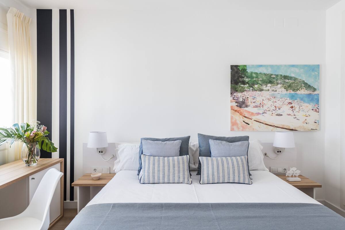 A hotel room with a bed, bedside tables, a desk, and a chair.