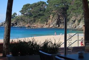 A beach view with a clear sky, rocky cliffs, and a few people on the sand. - Hotel Terramar (Palafrugell)