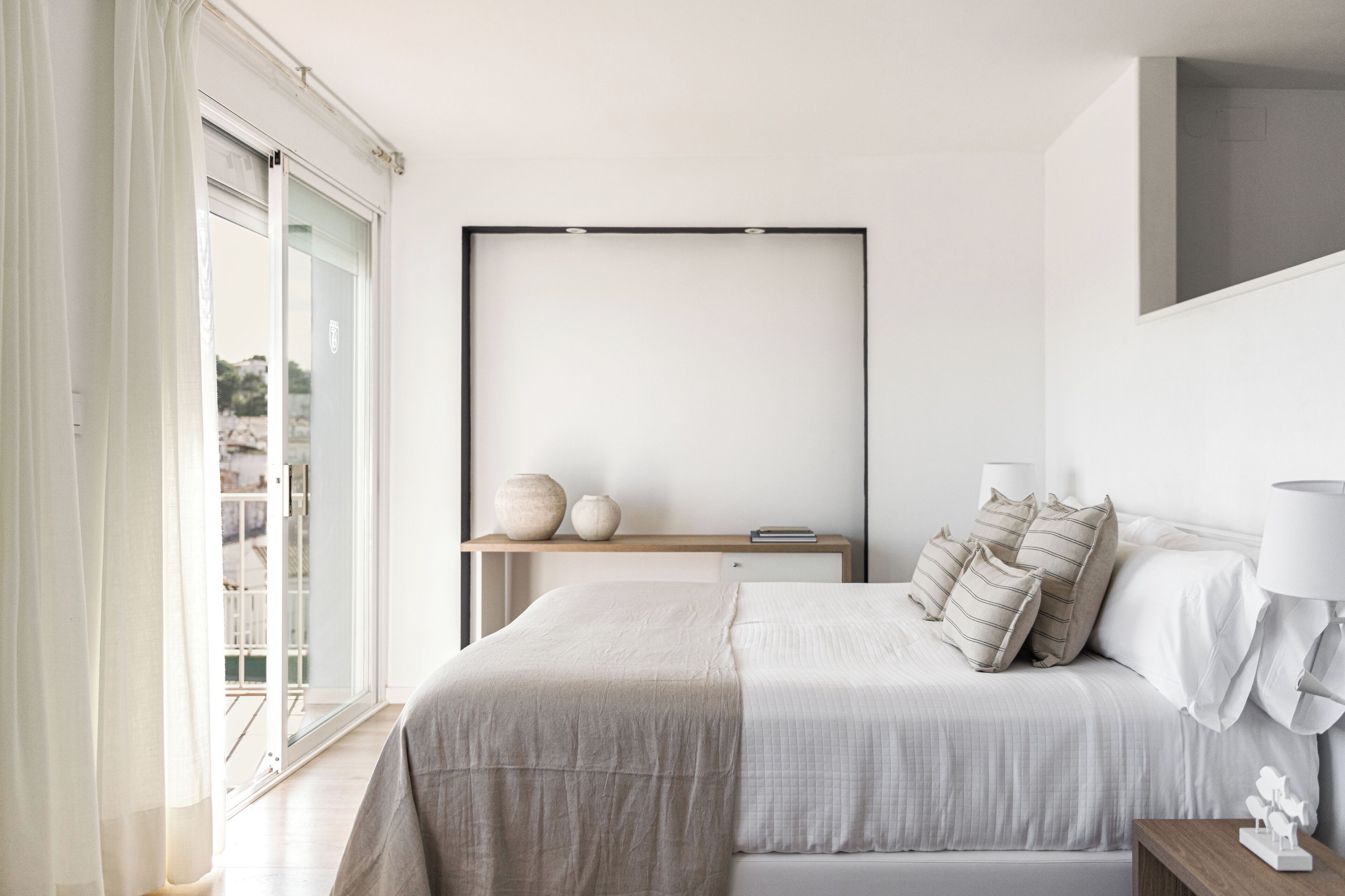 Un dormitorio con una cama grande, mesitas de noche y vistas a través de un ventanal corredero.