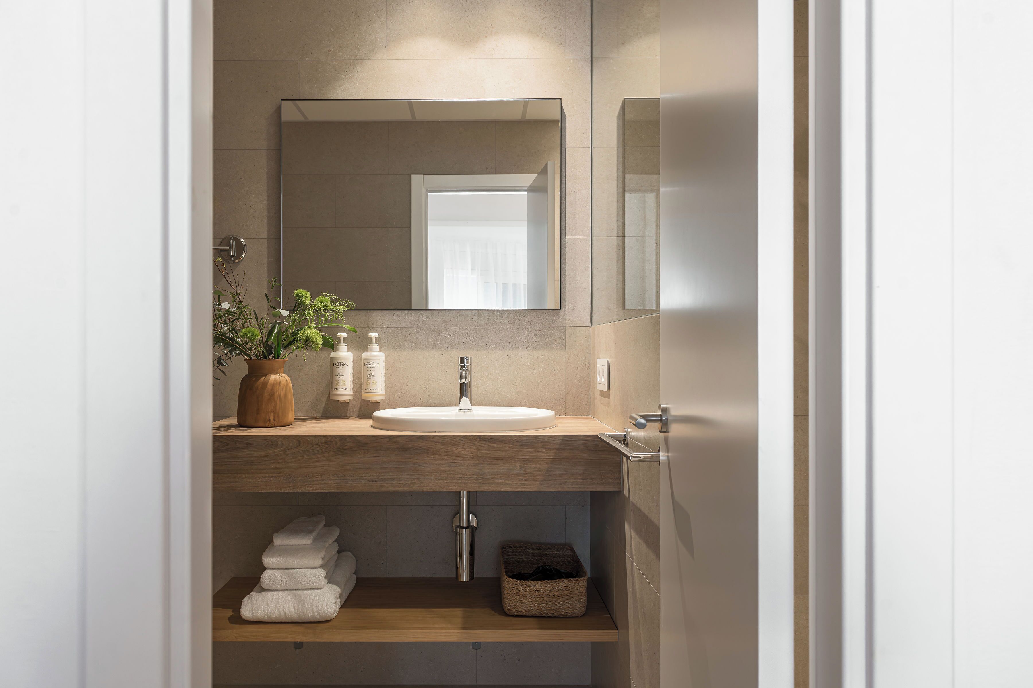 Un baño con tocador de madera, un lavamanos blanco, un espejo y un perchero para toallas.