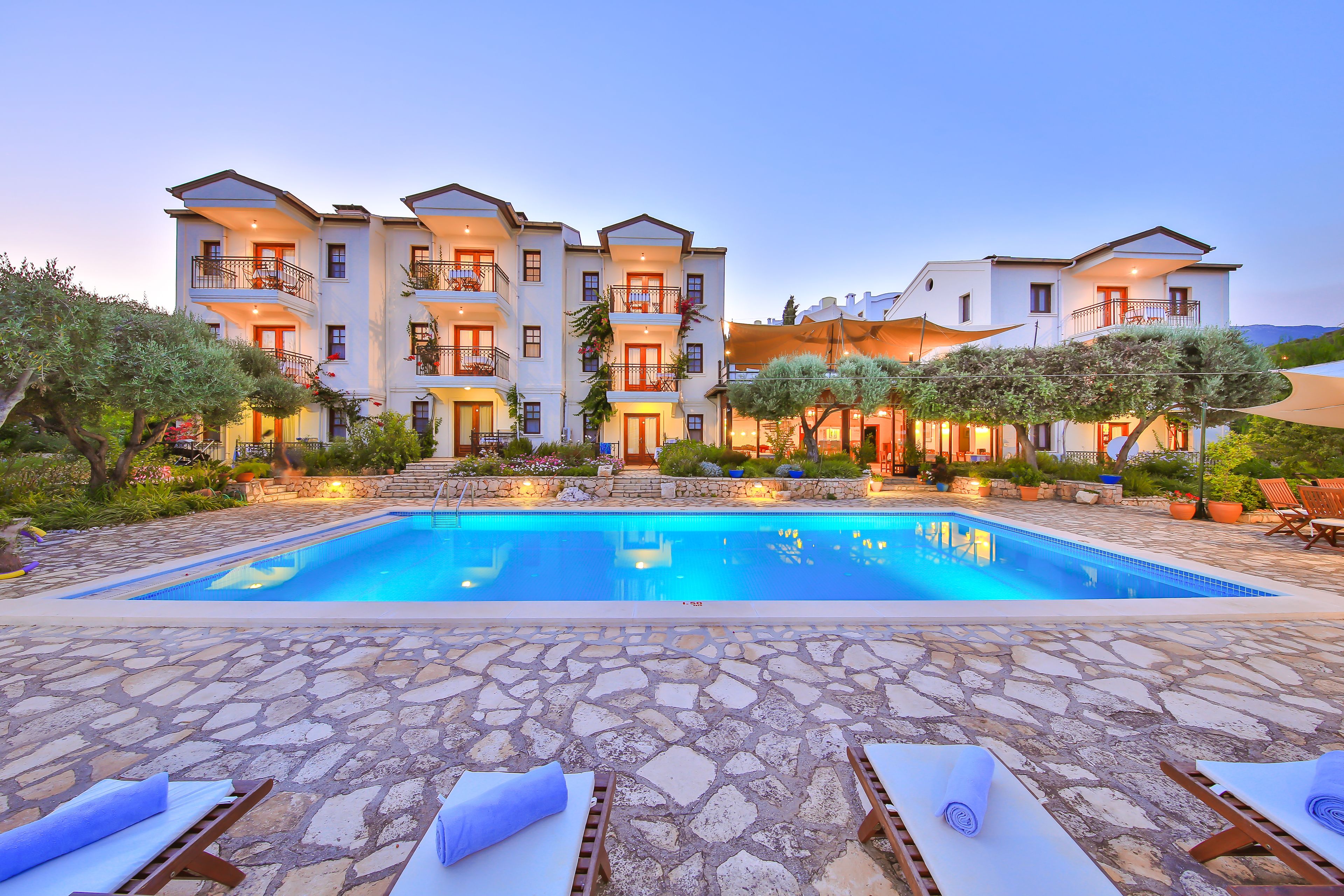 A hotel with a swimming pool, stone-tiled deck, and multiple balconies.