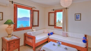 A room with two wooden sofas, a small table with a vase, and a lamp. - Diva Residence Hotel (Kas)