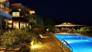 A nighttime swimming pool area with stone pathways, outdoor seating, and a building with a balcony. - Diva Residence Hotel (Kas)
