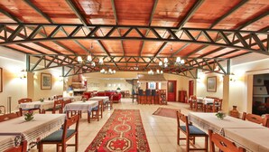 A spacious dining area with wooden tables and chairs, a central decorative rug, and a high wooden ceiling with exposed beams. - Diva Residence Hotel (Kas)