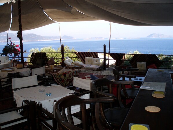 An outdoor seating area with a table and chairs, a view of the sea, and a mountainous backdrop. - Diva Residence Hotel (Kas)