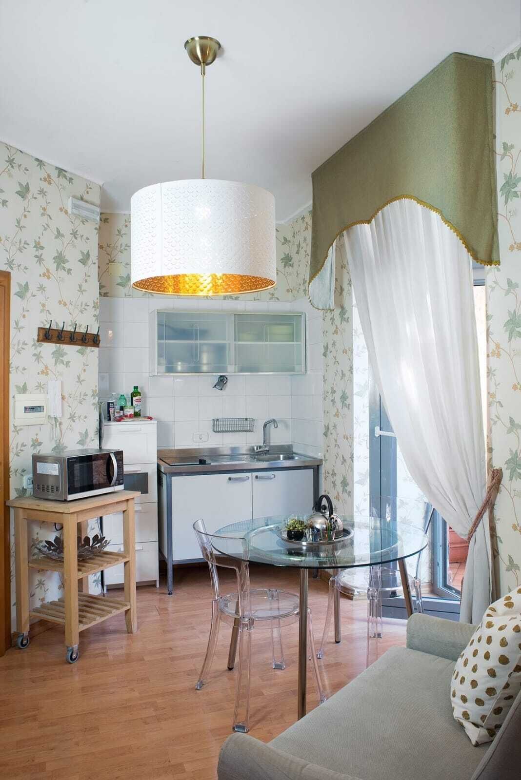 A compact kitchen with a microwave, a glass dining table, and a sofa.