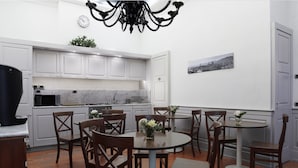 A modern kitchen with white cabinets, a marble countertop, and a dining area with wooden chairs and a round table. - Il Salotto di Firenze (Florence)