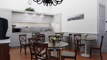 A modern kitchen with white cabinets, a marble countertop, and a dining area with wooden chairs and a round table.