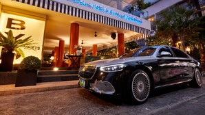 Um carro de luxo estacionado em frente a um hotel boutique com um letreiro chamativo 'BYD'.