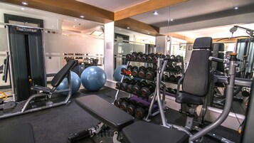 A gym with exercise equipment, including dumbbells, exercise balls, and a treadmill.