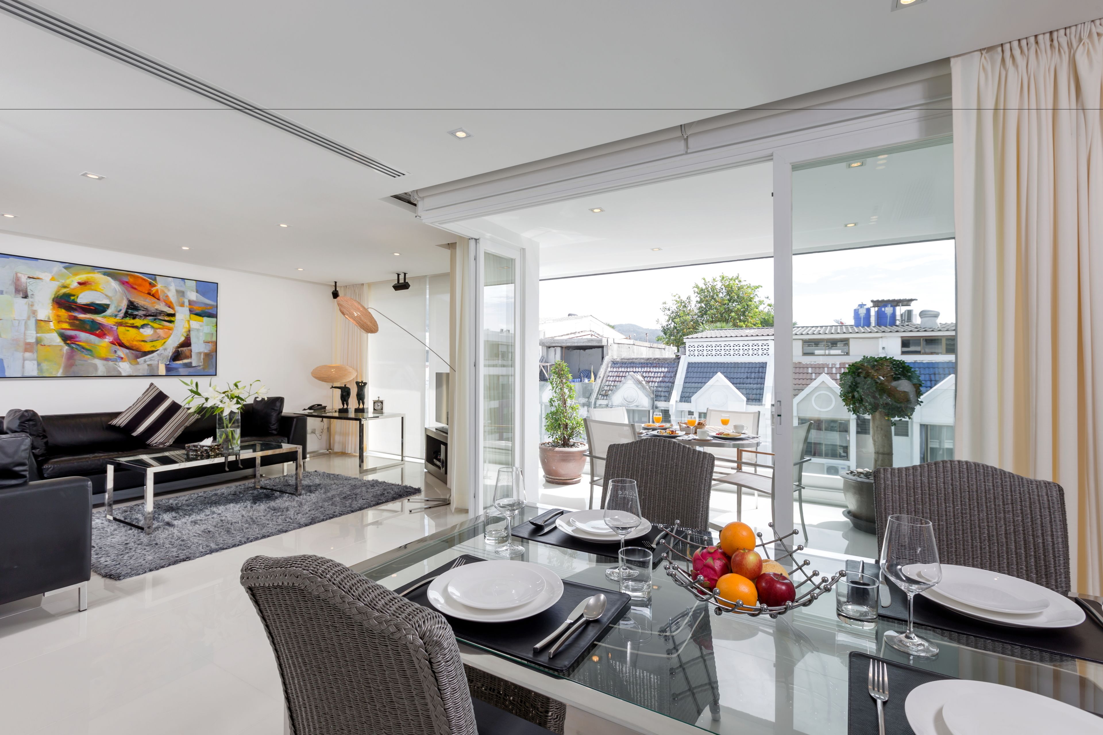 A modern dining area with a glass table, black chairs, and a view of the cityscape.
