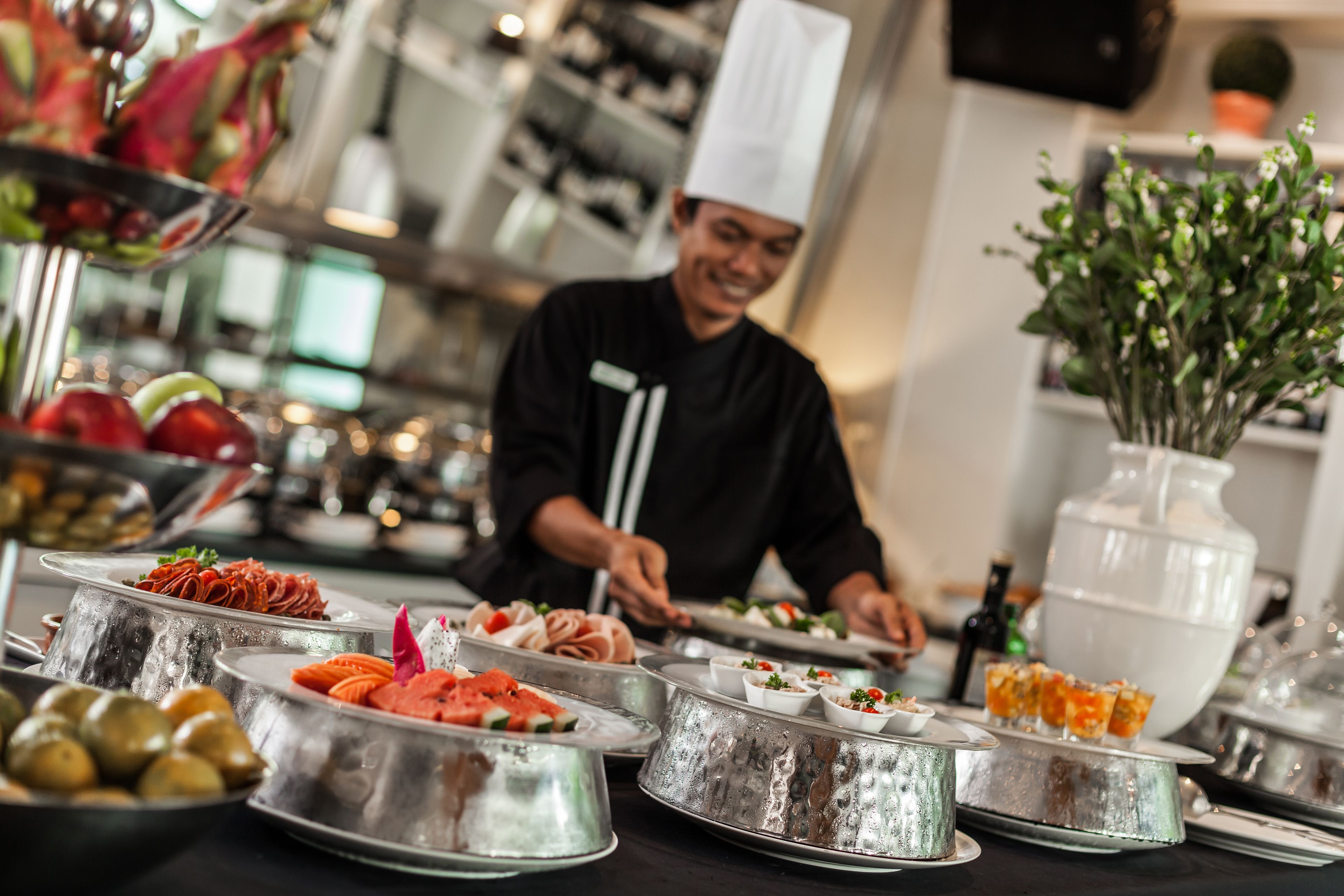 A buffet setup with various food items and a chef preparing food.
