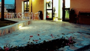 An outdoor patio area with a stone floor, several chairs, and potted plants. - Métà hotel (Santa Teresa di Gallura)