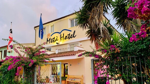 A hotel entrance with a sign reading "Metá Hotel," a gated entrance, and a paved pathway leading to the building. - Métà hotel (Santa Teresa di Gallura)