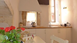 Una cocina con encimera de madera, hervidor, cafetera, fregadero y armarios.
