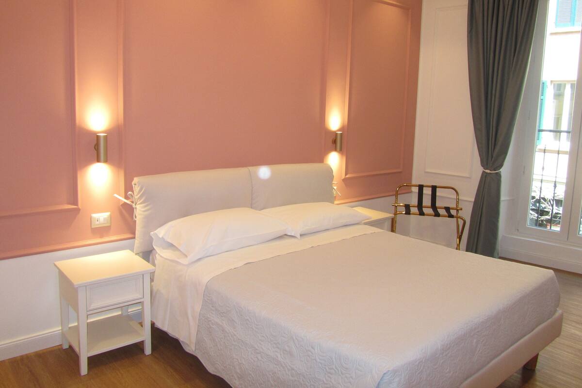 Une chambre à coucher avec un lit, des tables de chevet et des lampes fixées au mur.