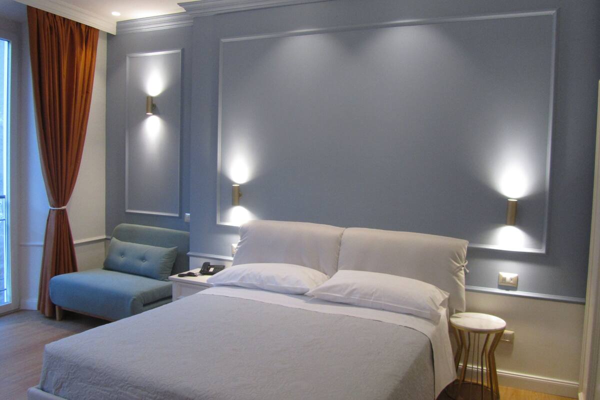 Une chambre d’hôtel avec un grand lit, une table de chevet avec une lampe, une petite table ronde et une chaise.