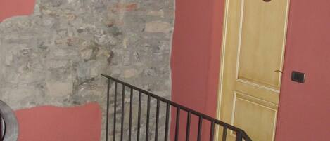 A staircase with a stone wall, a wooden door, and a metal railing.