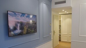 A bedroom with a large TV mounted on the wall displaying a waterfall scene. - Hotel Borgovico (Como)