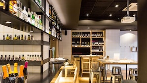 A modern bar area with shelves of various liquor bottles, a bar counter, and seating arrangements. - Rooms Ciencias (Valencia)