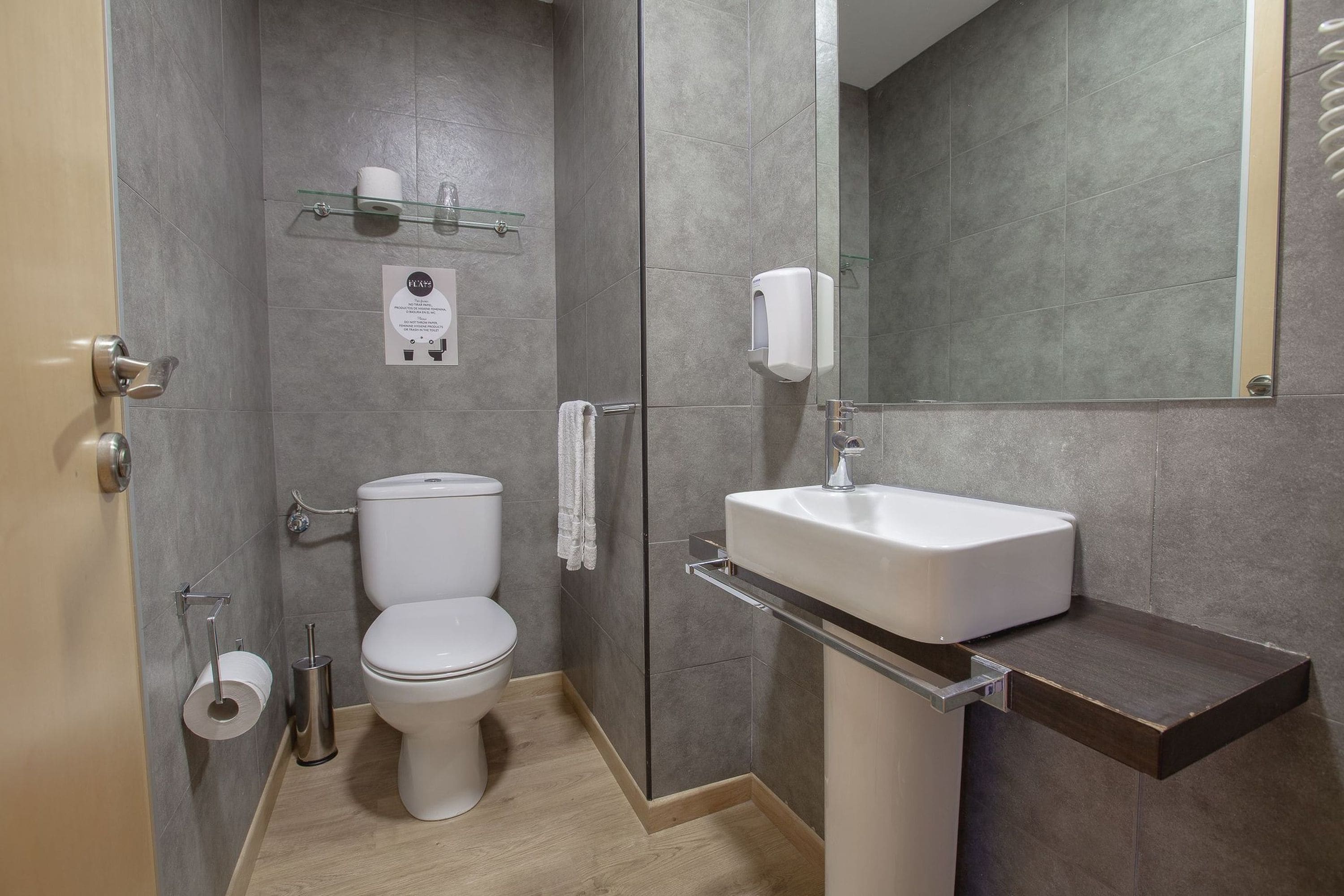 Une salle de bain moderne équipée de toilettes, d’un lavabo et d’une douche à parois de verre.