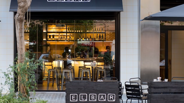 An outdoor seating area with a sign reading "ELBAR" and a bar visible inside. - Rooms Ciencias (Valencia)