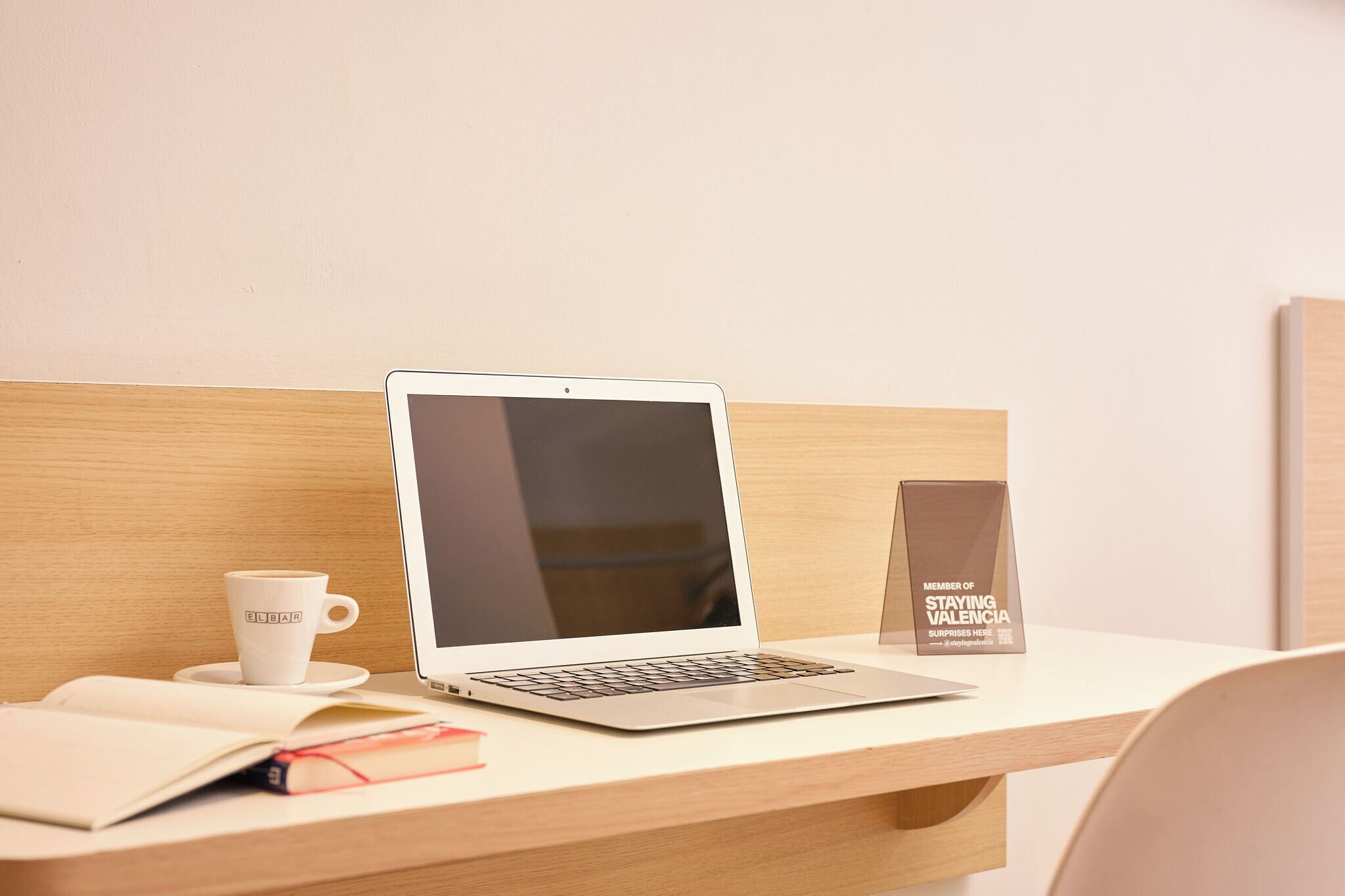 Un ordinateur portable sur un bureau en bois, une tasse blanche et une carte de membre.