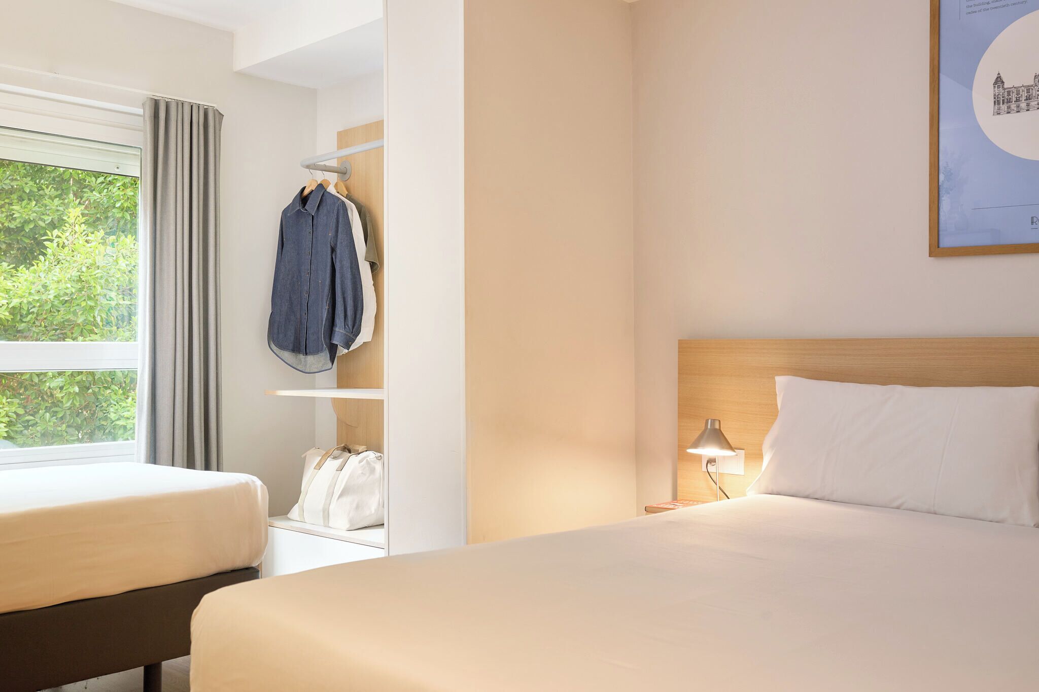 A hotel room with two beds, a wardrobe, a nightstand, and a window with curtains.