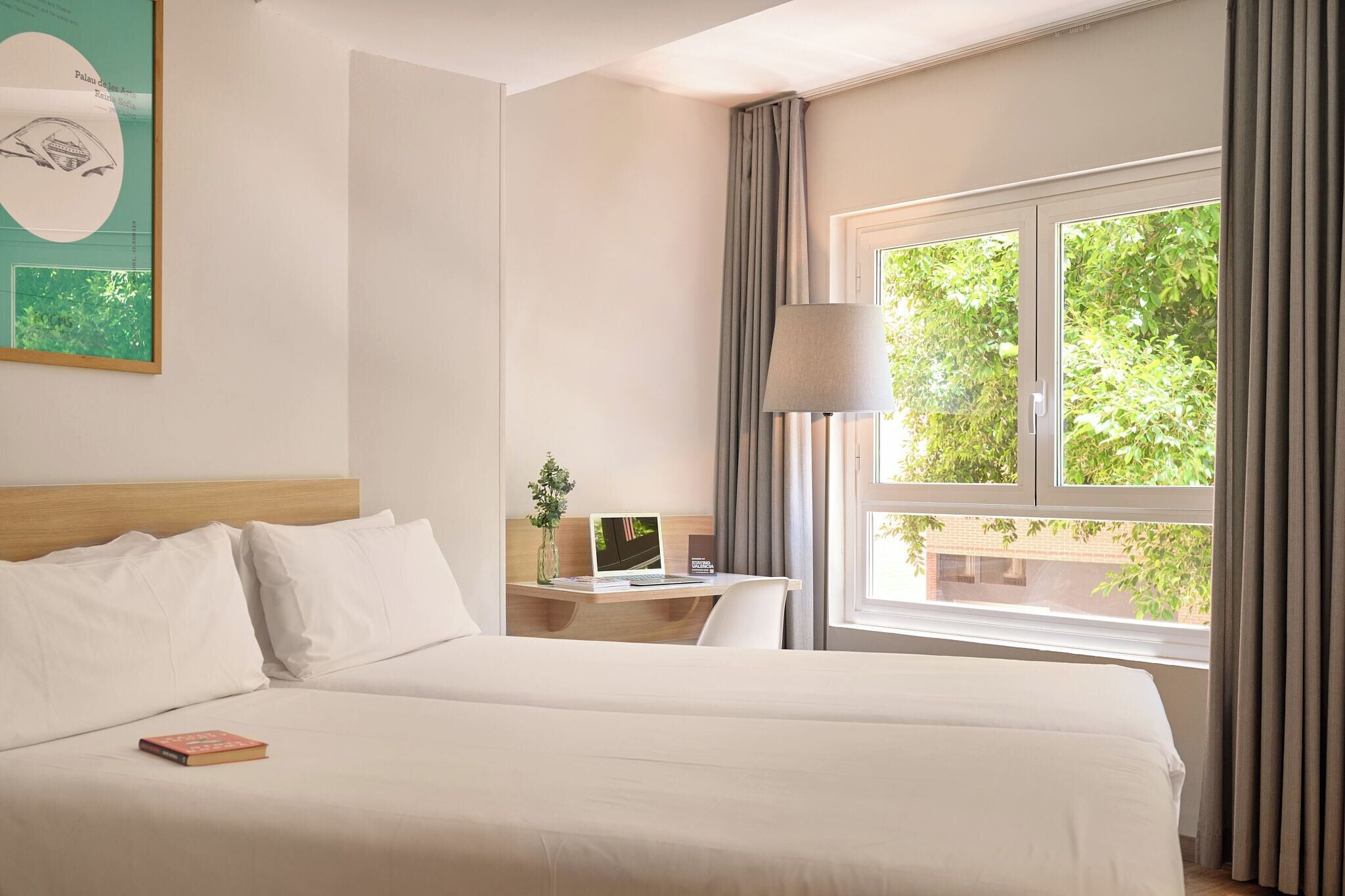 Una habitación de hotel con cama, escritorio y ventana con cortinas.
