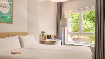 Una habitación de hotel con cama, escritorio y ventana con cortinas.