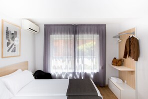 Una habitación de hotel con una cama, un escritorio y un ventanal con cortinas.