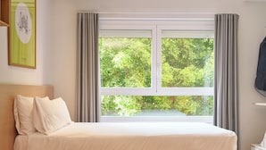 A neatly made bed with white linens, a window with curtains, and a framed picture on the wall. - Rooms Ciencias (Valencia)