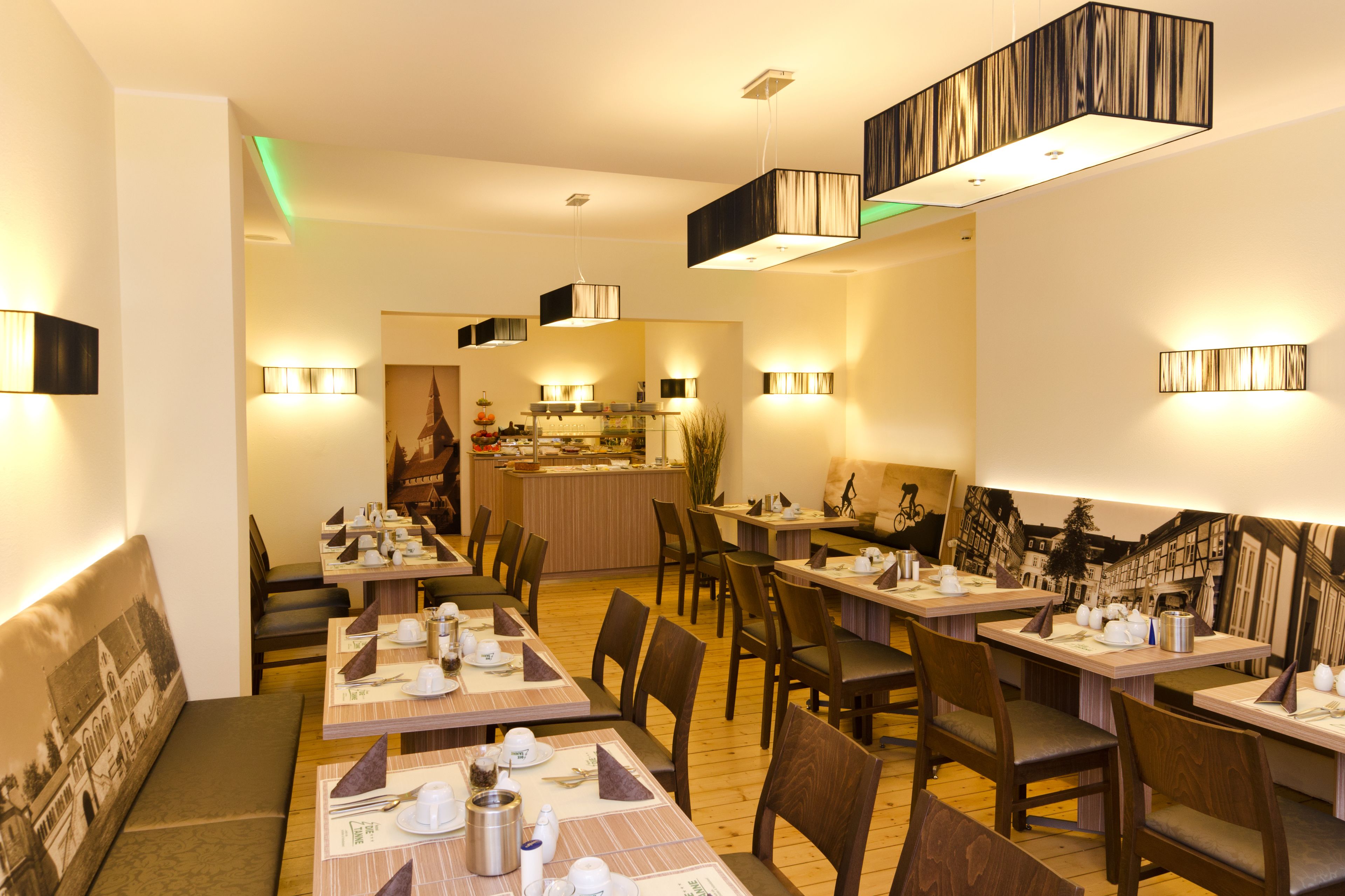 Ein Restaurant mit mehreren Tischen, Stühlen, einer Bar und Wandleuchten.