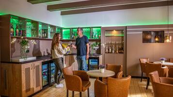 Una zona de bar con armarios de madera, un refrigerador y sillas color naranja.