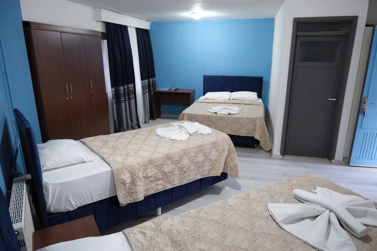 Une chambre d’hôtel avec deux lits, une armoire, un bureau et une porte.