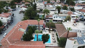 An aerial view of a residential area with a central swimming pool surrounded by buildings with red-tiled roofs.