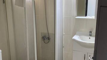 A bathroom with a glass-enclosed shower, a white sink, and a toilet.