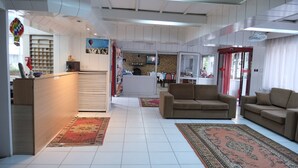 A hotel lobby with a reception desk, sofas, a TV, and a fireplace.