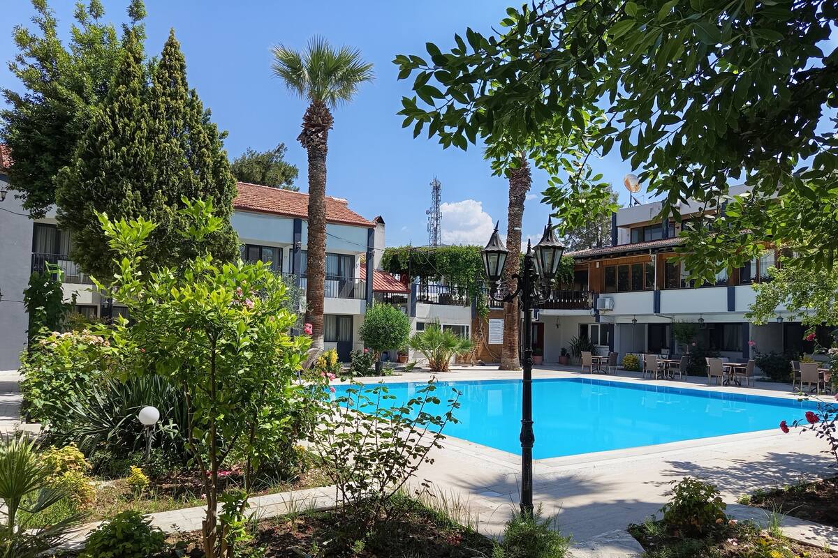 Une piscine entourée de verdure et de bâtiments dotés de balcons.