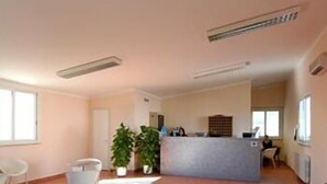 A spacious room with a reception desk, white chairs, and potted plants. - Autohotel Ravenna (Ravenna)