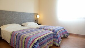 A room with two beds, each with a colorful quilt, a grey headboard, and a wall-mounted light fixture. - Autohotel Ravenna (Ravenna)