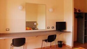 A room with a long desk, two chairs, a television, and a mirror. - Autohotel Ravenna (Ravenna)