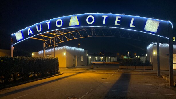 An auto hotel entrance with a large illuminated archway and a parking area. - Autohotel Ravenna (Ravenna)