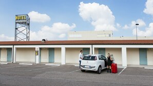 A hotel with a signboard, a parking lot, and a building with multiple doors. - Autohotel Ravenna (Ravenna)
