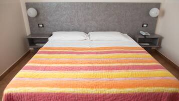 A hotel room with a large bed, two bedside tables, and a headboard.